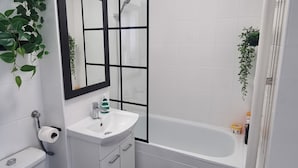 Et moderne badeværelse med toilet, håndvask og badekar.