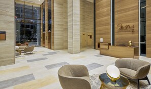 A modern lobby with a reception desk, two armchairs, and a coffee table. - Midtown The Peak By Dhome (Ho Chi Minh City)