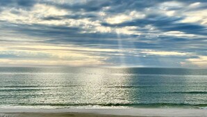 A beach with a view of the ocean and a cloudy sky.
