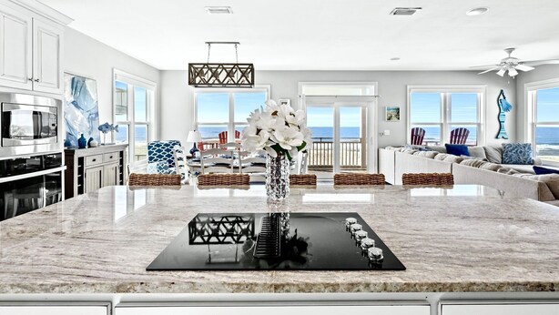 A modern kitchen with a central island, large windows, and a view of the ocean.