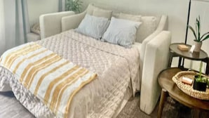 A bedroom with a large bed, a bedside table, a lamp, and framed pictures on the wall.