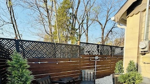 A patio with outdoor furniture, a decorative fence, and potted plants.