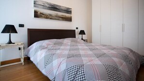 A bedroom with a bed, bedside tables, a wardrobe, and artwork on the wall. - House in the Olive Trees-For a relaxing vacation at the lake. (Lombardia)