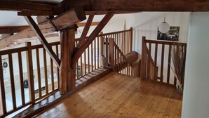 A wooden staircase with a railing, leading to a balcony with a view of the outside. - 3 Peaceful Country Gites - Sleeps 16 with 2 Wood-Fired Hot Tubs & Swimming Pool (Melle)