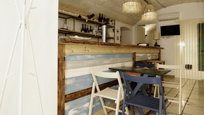 A restaurant with a rustic wooden bar, white and blue chairs, and hanging wicker chandeliers. - A Stare [Stone Apartment - Historic Center - Molfetta] (Molfetta)