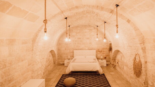 A cozy, stone-walled bedroom with a bed, bedside tables, and hanging lights. - A Stare [Stone Apartment - Historic Center - Molfetta] (Molfetta)