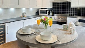 Un îlot de cuisine avec deux bols, deux cuillères, un verre de jus d’orange, un verre d’eau et une théière à motifs floraux.