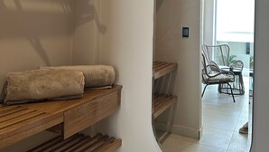 A modern interior with wooden shelves, a mirror, and a view of a balcony with wicker furniture. - Cabañas Covemar (Coveñas)