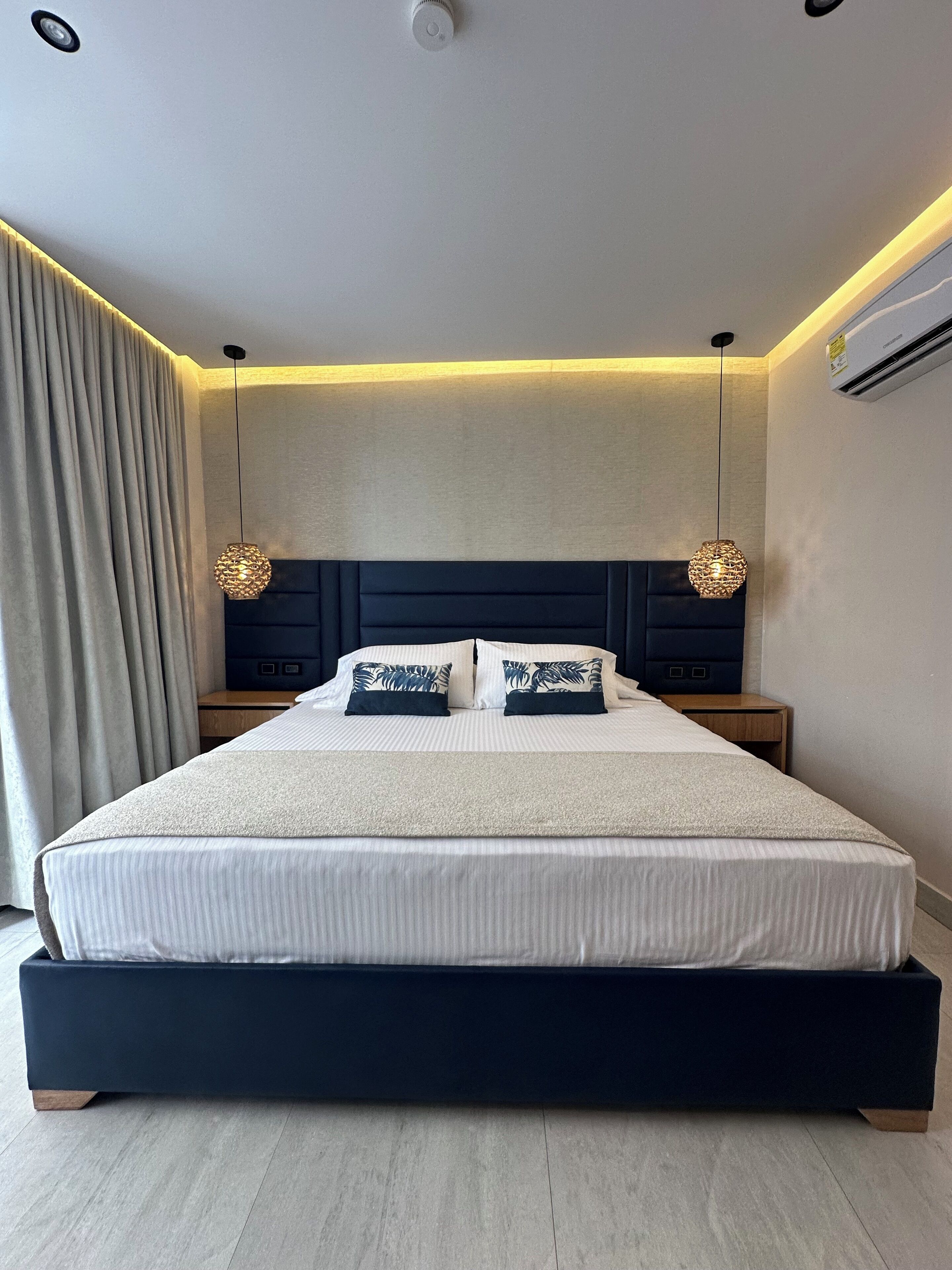 A modern bedroom with a large bed, two bedside tables, and a headboard.