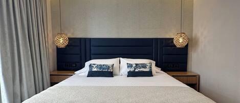 A modern bedroom with a large bed, two bedside tables, and a headboard.