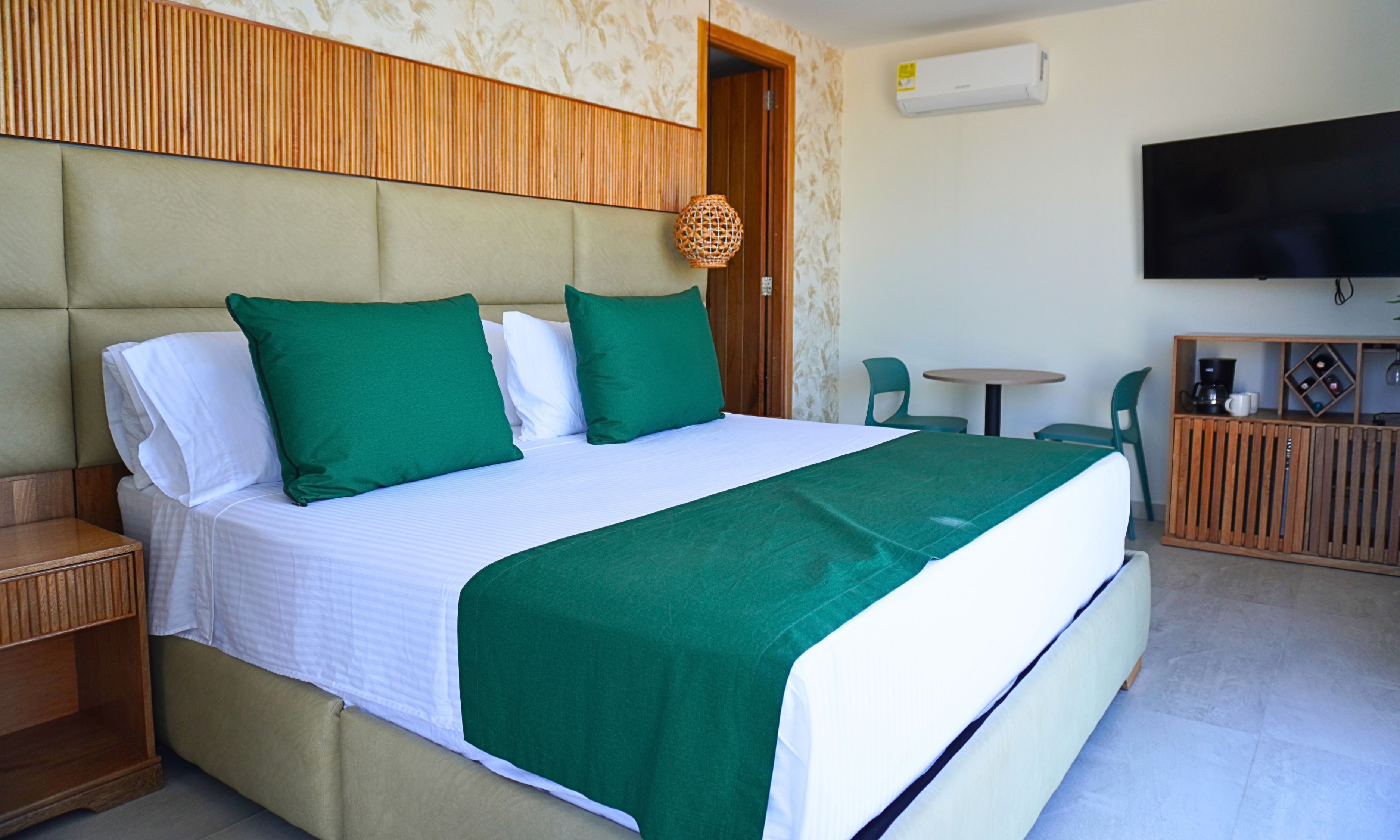Una habitación de hotel con una cama, televisor, una mesita y sillas.