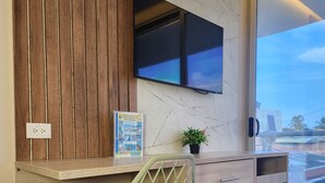 A modern kitchen with a wooden accent wall, a built-in TV, a small fridge, and a potted plant. - Cabañas Covemar (Coveñas)