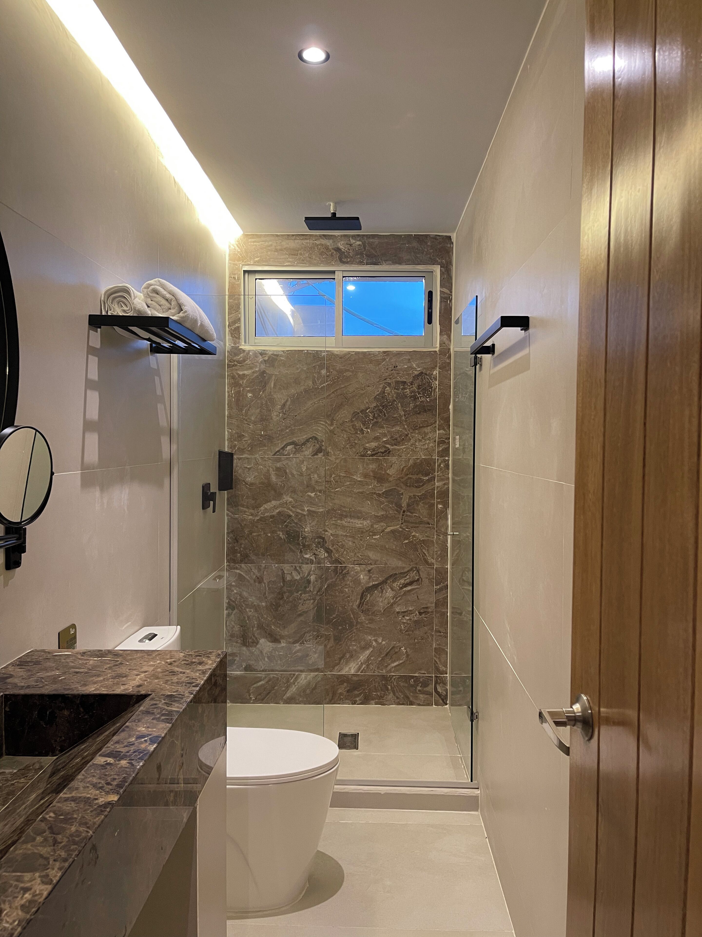 Un bany modern amb dutxa de marbre, un vàter i un lavabo amb mirall.