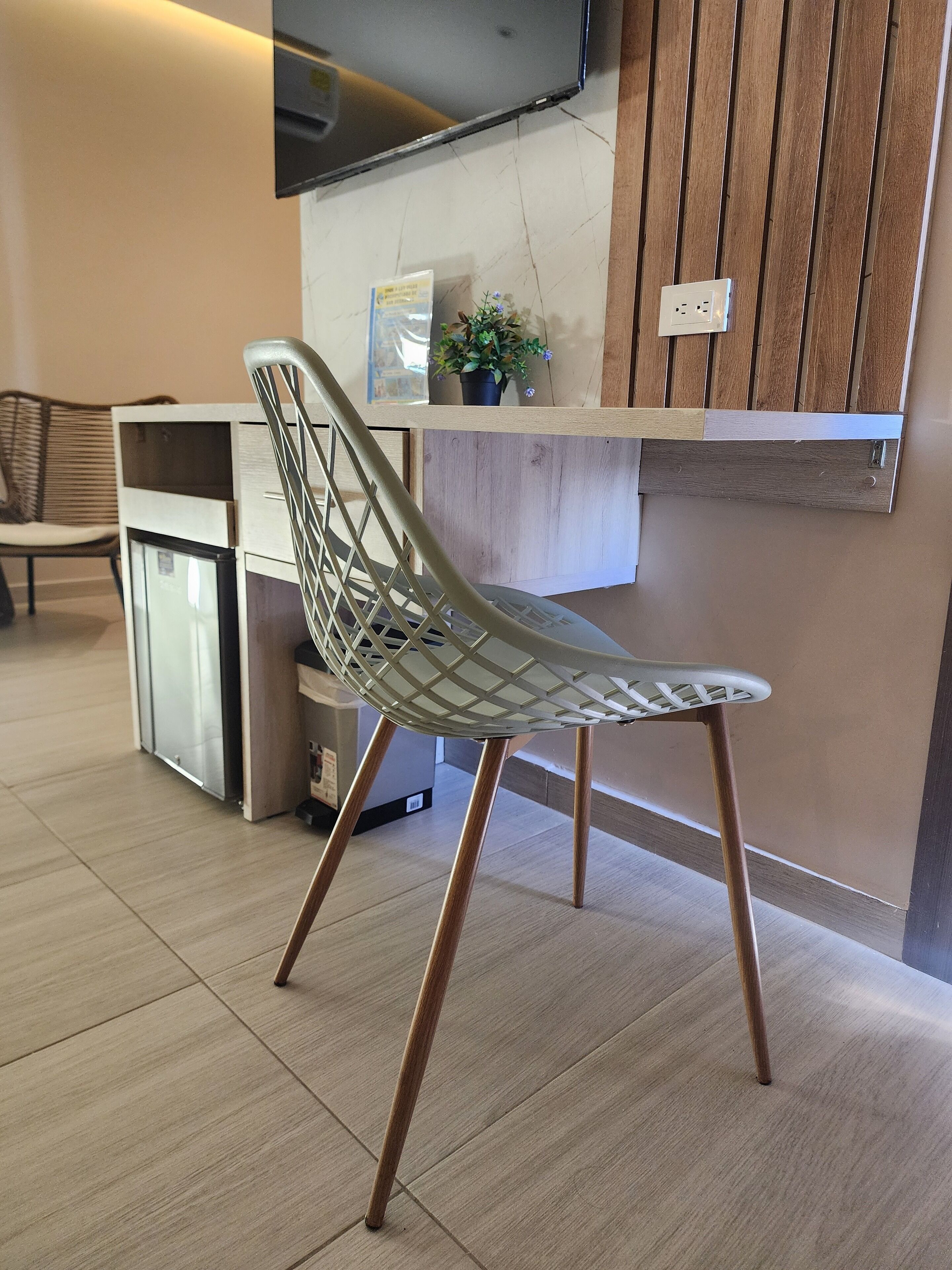 Un espace d’accueil moderne, doté d’un comptoir de réception en bois, d’une cloison en verre et d’une chaise en métal au dossier à motifs géométriques.