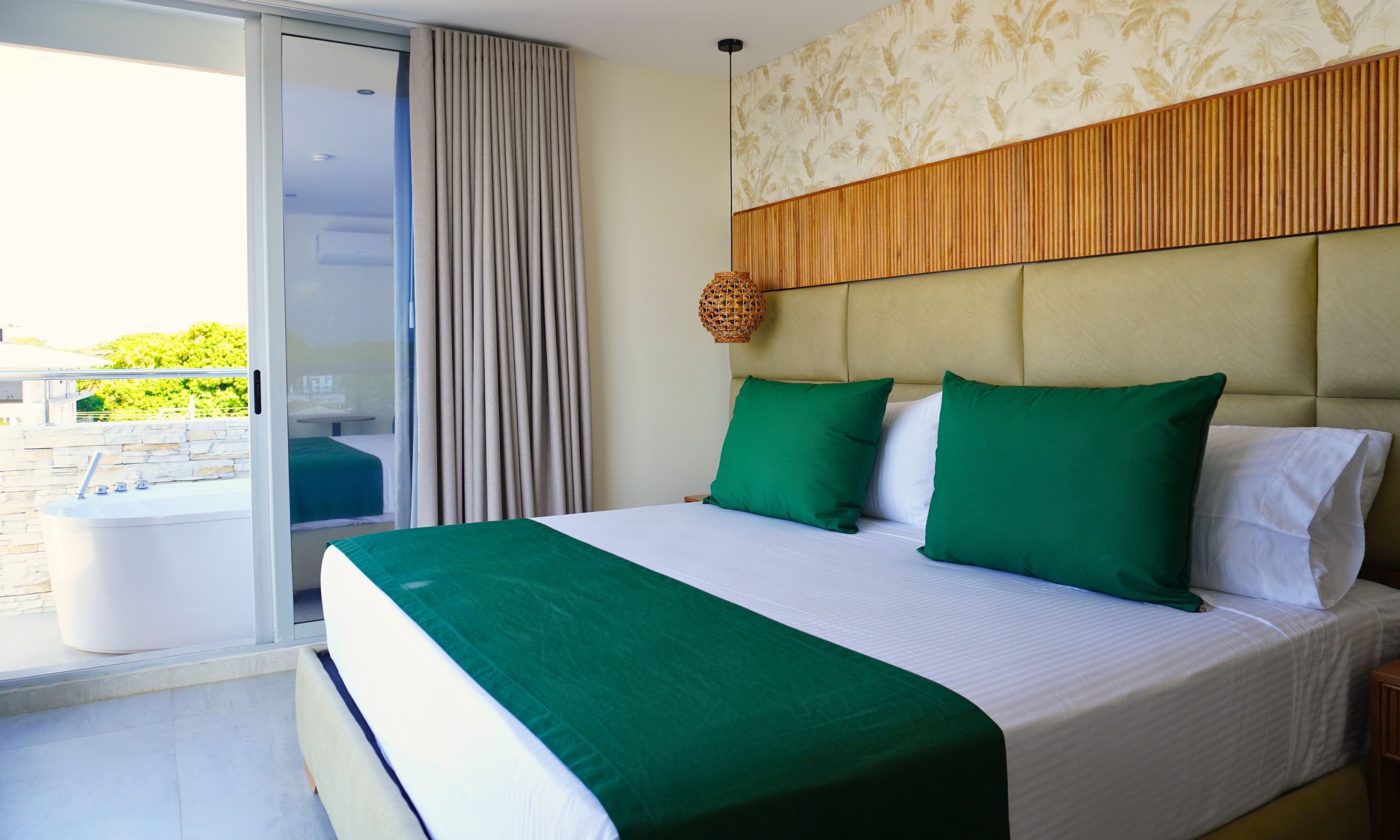 Habitación de hotel con una cama, un ventanal y vistas a zonas verdes.