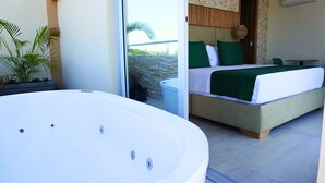 A modern hotel room with a large bathtub, a bed with green bedding, and a view of the outdoors. - Cabañas Covemar (Coveñas)