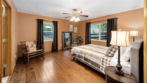 A bedroom with a bed, a rocking chair, a ceiling fan, and a window with curtains. - Nellies Cottage is 4 miles from WEC-World Equestrian Center (Ocala)