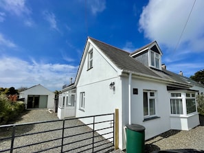 A white two-story house with a sloped roof, a visible chimney, and a small attached garage.