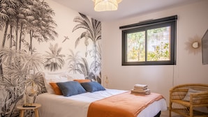 A bedroom with a bed, a window, a wall mural, a chair, and a lamp. - Apartment 2: Cap Lardier (Roquebrune-sur-Argens)