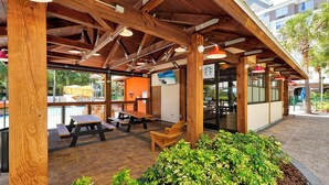 An outdoor patio area with wooden tables and benches, surrounded by greenery. - Key West Vibe & Disney Thrills: Tropical Condo w/ Water Park (KIssimmee)