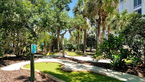 A landscaped garden with pathways, palm trees, and a signpost. - Key West Vibe & Disney Thrills: Tropical Condo w/ Water Park (KIssimmee)
