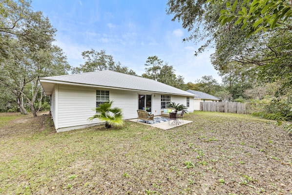A single-story house with a covered patio, surrounded by trees and a wooden fence. - Lillian House (Pensacola)