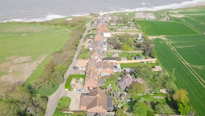 Vista aérea de una zona residencial costera con casas, una carretera y campos verdes.
