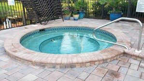 A circular pool with a tiled edge, surrounded by a brick patio. - Modern Condo with easy beach access in the heart of Naples Park (Naples)