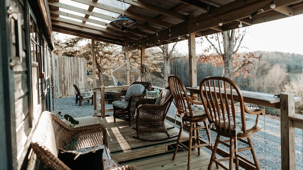 Un área de estar al aire libre techada, con mobiliario de mimbre y una mesa de madera.
