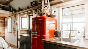 Una cocina con un refrigerador rojo, armarios de madera, un fregadero y un ventanal con vistas.