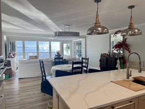 A modern kitchen with a marble countertop, stainless steel appliances, and pendant lighting.