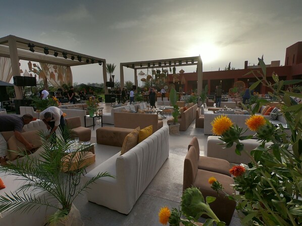 An outdoor seating area with sofas and tables, surrounded by plants and decorative elements. - Dar Noujoum (Ghmate)