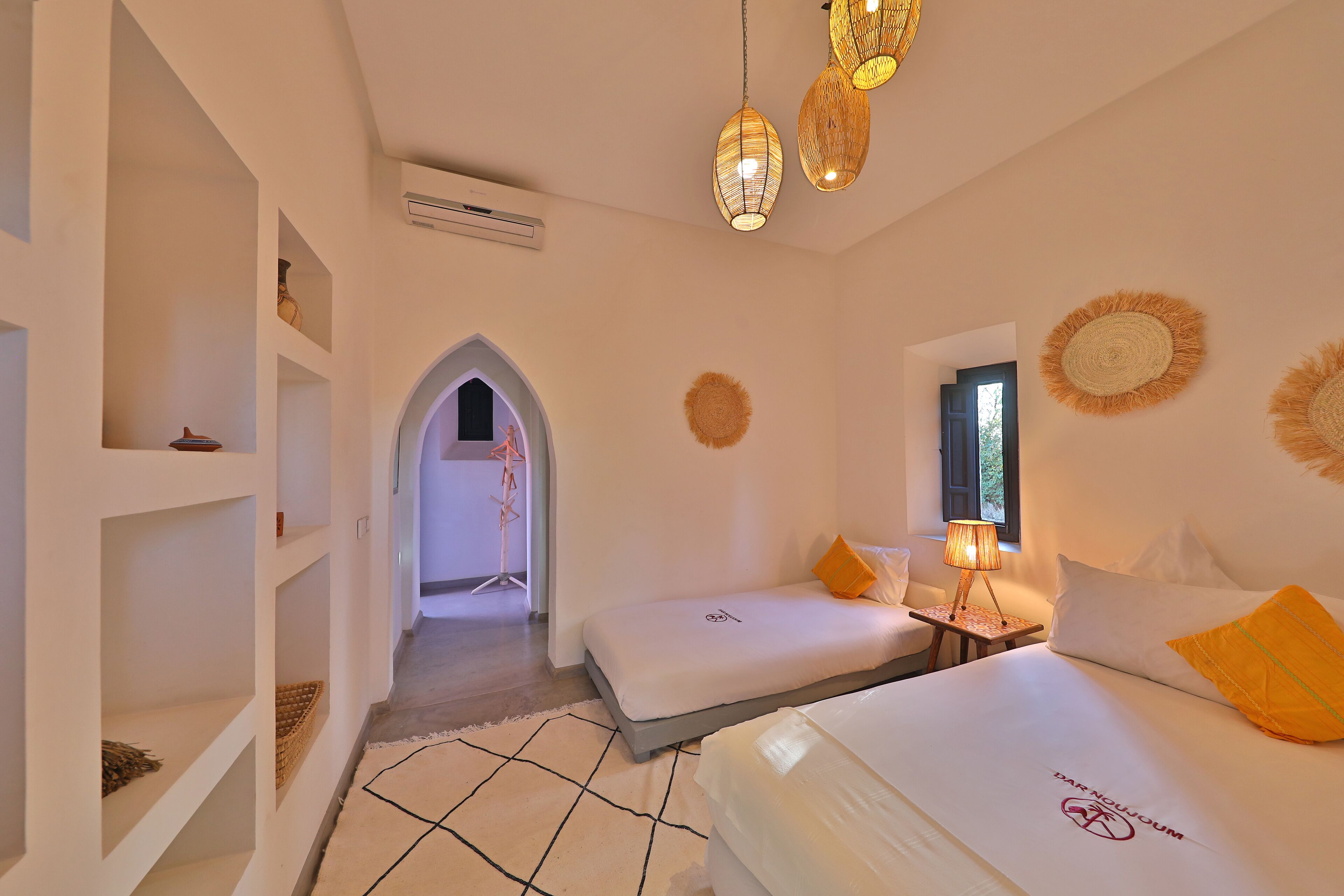 Habitación de hotel con dos camas, una mesita, una lámpara y adornos en la pared.