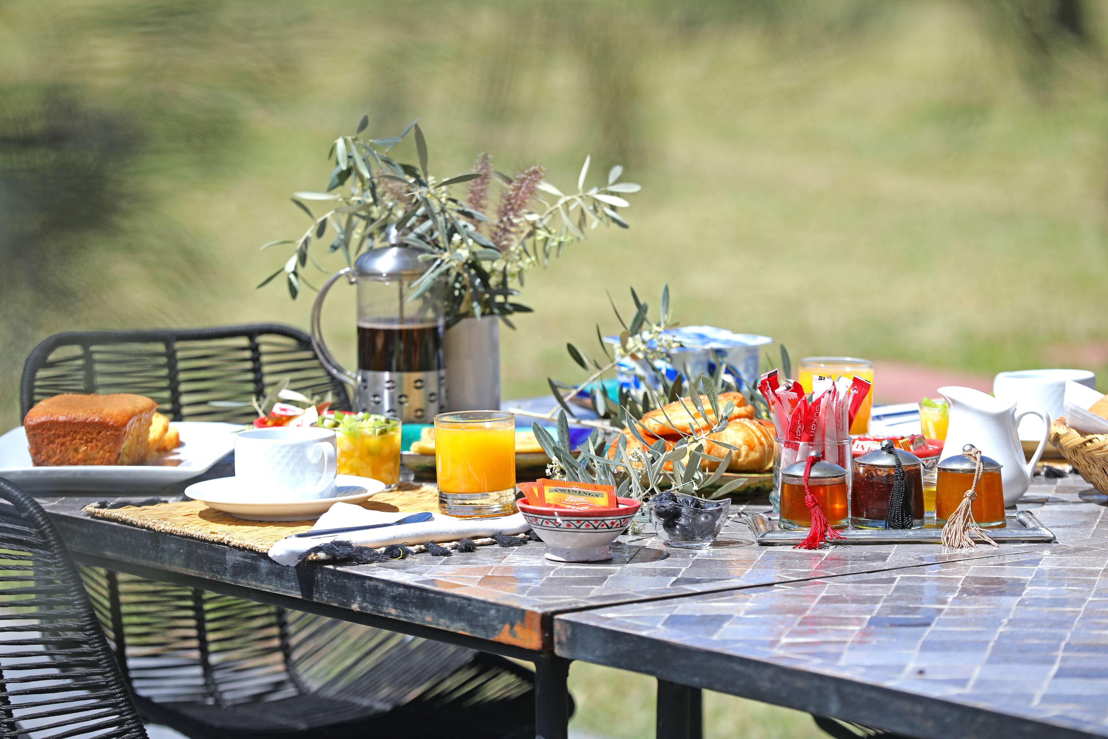 A breakfast table with various food items, drinks, and a coffee maker.