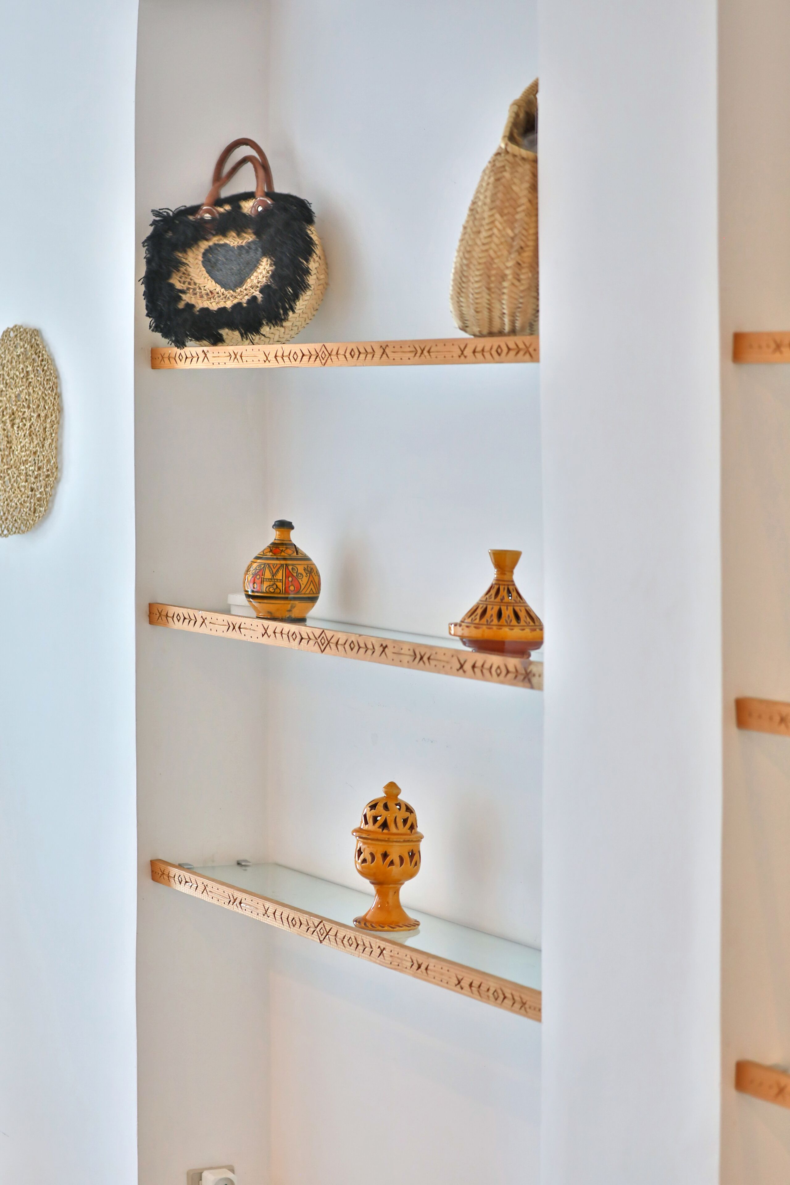 A shelf with decorative items including a woven basket, a small vase, and a ceramic jug.