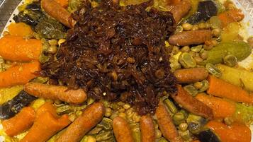 A large platter of assorted vegetables and sausages on a patterned plate.