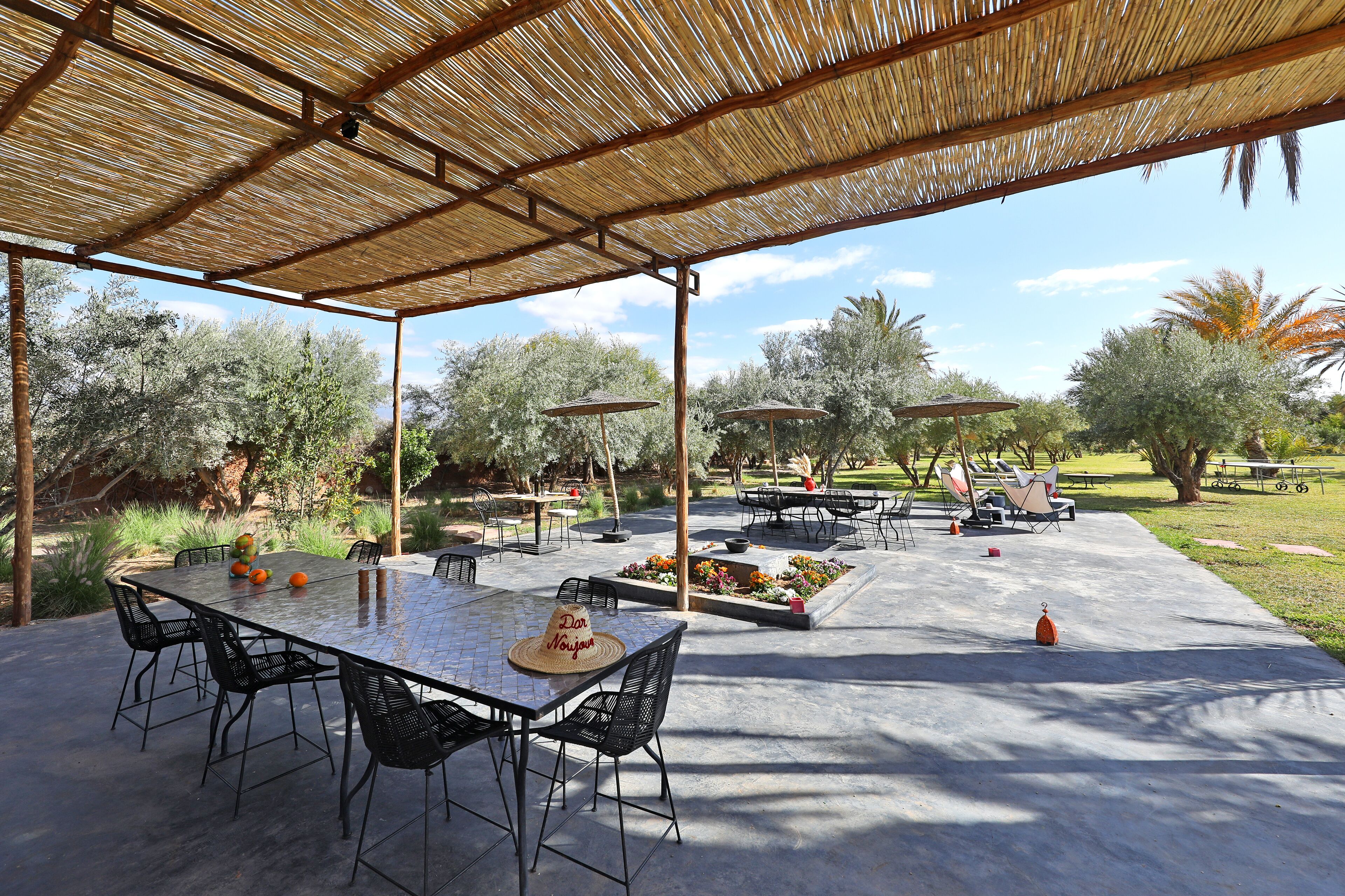 An outdoor patio with a covered dining area, tables, chairs, and umbrellas.