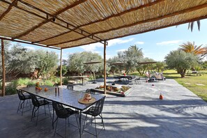 An outdoor patio with a covered dining area, tables, chairs, and umbrellas.