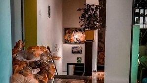 Un pasillo con piso de madera en patrón de espiga, una planta en maceta con flores y un cuadro en la pared.