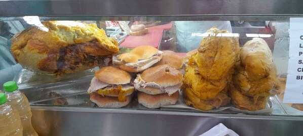 A display case with various fried foods, including sandwiches and chicken.