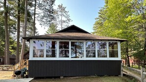 A small wooden cabin with a gabled roof and large windows, surrounded by trees. - Charming Cedar Lakeside Cottage at Elbert's Resort (Saint Germain)
