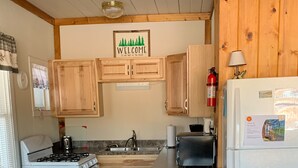 A compact kitchen with wooden cabinets, a gas stove, a sink, and a refrigerator. - Charming Cedar Lakeside Cottage at Elbert's Resort (Saint Germain)