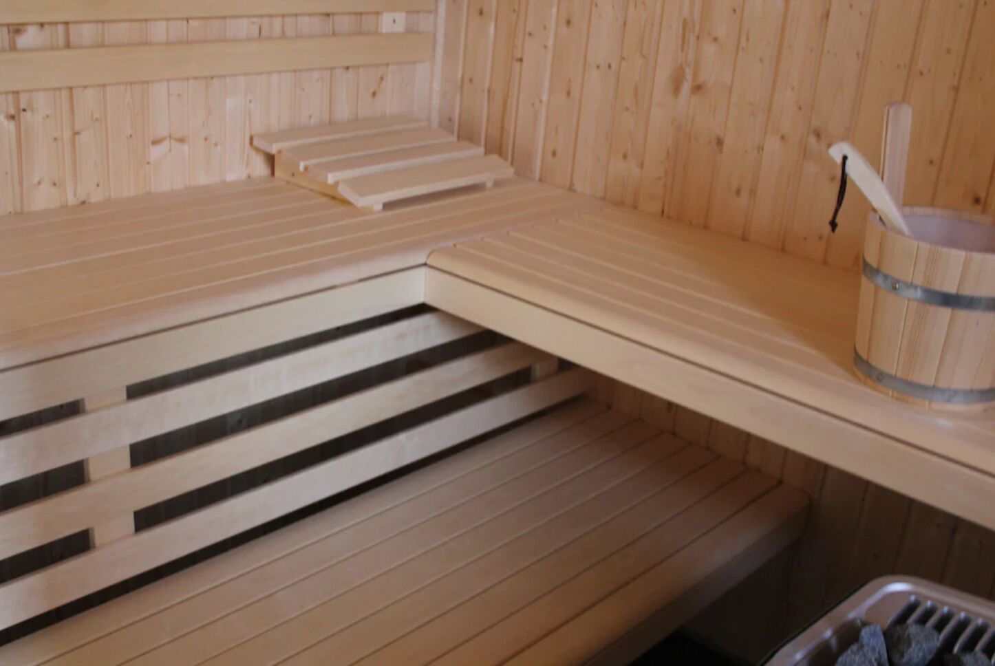 A sauna with wooden benches and a bucket.