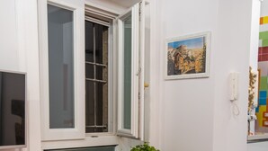 A room with a window, a shelf with towels, a plant, and a colorful wall. - Nidomare (Salerno)