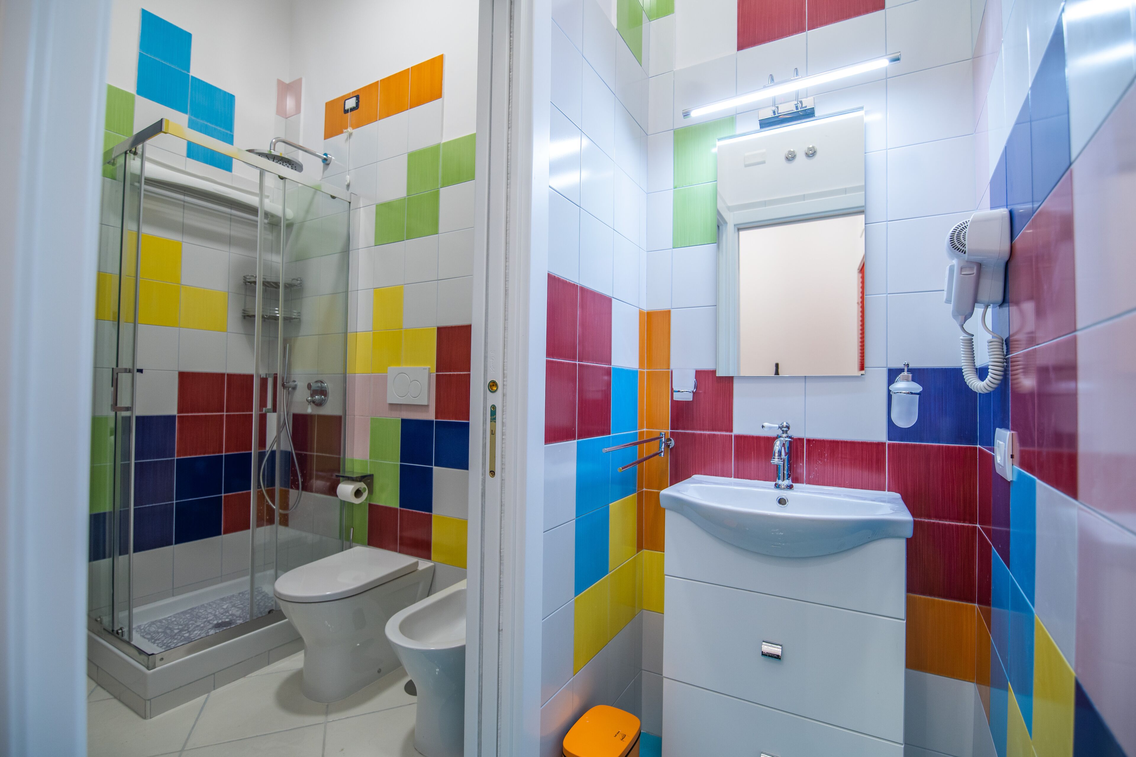 A bathroom with a glass shower enclosure, a toilet, and a sink with a mirror above it.