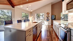 A modern kitchen with a large island, stainless steel appliances, and pendant lighting.
