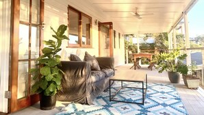 Une véranda abritée avec un canapé, une table basse et des plantes en pot.
