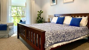 Une chambre à coucher avec un lit, une fenêtre avec des rideaux, une plante et deux tableaux encadrés accrochés au mur.