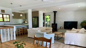 Un salon moderne avec une table à manger en bois, deux canapés, un fauteuil à rayures et un téléviseur.