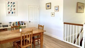 Un coin repas avec une table et des chaises en bois, une bibliothèque remplie de livres et des tableaux encadrés accrochés au mur.